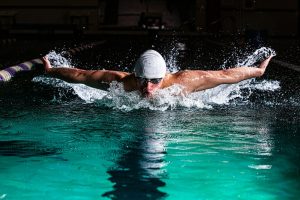 Photo by Gabriel Meinert a man swimming in a pool with a hat on