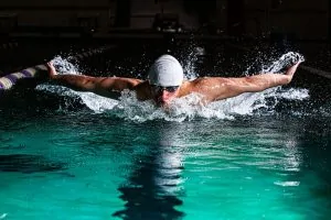 Photo by Gabriel Meinert a man swimming in a pool with a hat on